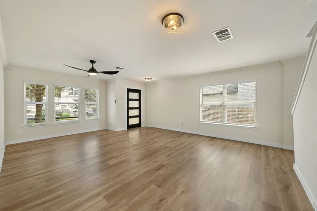 an empty room with wooden floor and windows