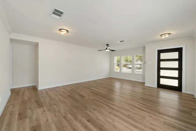 an empty room with wooden floor and windows