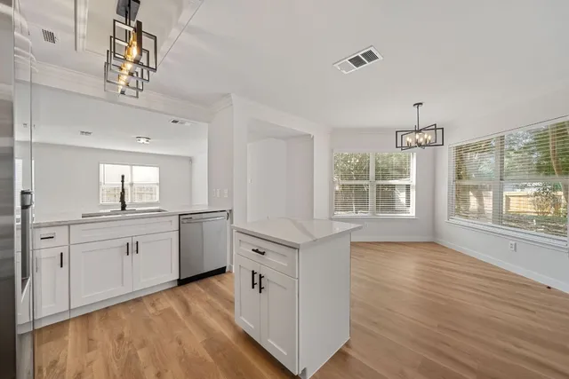a large white kitchen with granite countertop a stove a sink a window and white cabinets