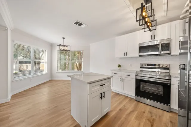 a kitchen with stainless steel appliances granite countertop a stove sink microwave and window
