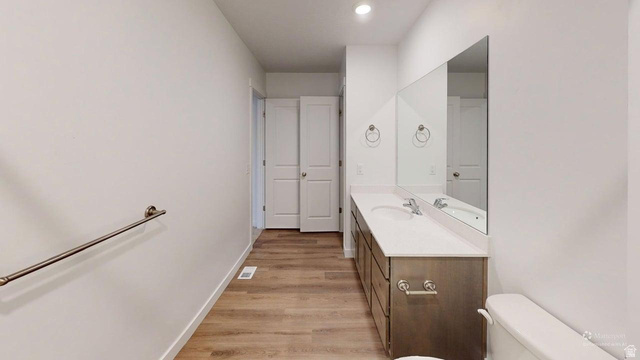 777 Pheasantbrook Drive, Unit 2B Centerville, UT 84014 - Photo 16 of 42 Bathroom featuring a double vanity with undermount sinks, a large mirror, a toilet, and wood-finish flooring
