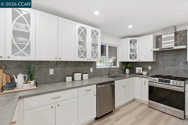 a kitchen with stainless steel appliances granite countertop a sink and cabinets with wooden floor