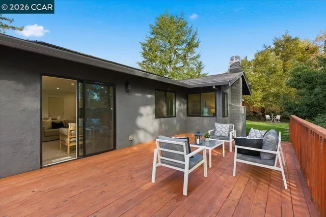 a view of house with outdoor seating and trees in the background