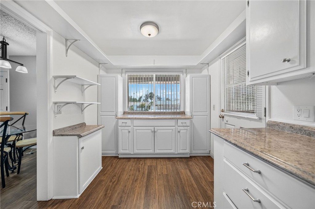 29078 Bradley Road Menifee, CA 92586 - Photo 19 of 42 a kitchen with stainless steel appliances granite countertop a stove a sink and white cabinets with wooden floor