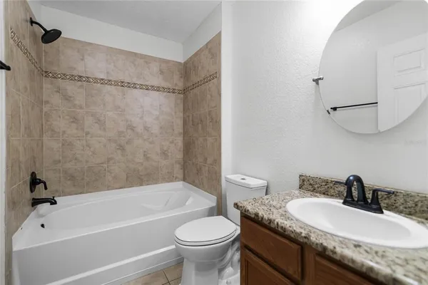 a bathroom with a granite countertop sink toilet mirror and bathtub