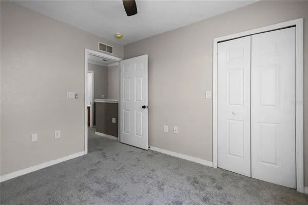 an empty room with ceiling fan and windows