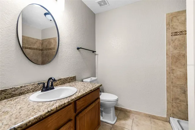a bathroom with a granite countertop sink a toilet and a mirror