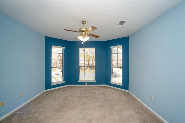 an empty room with windows and ceiling fan