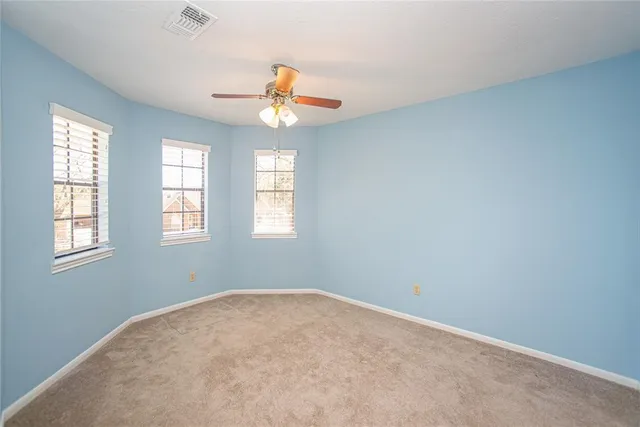 an empty room with windows and ceiling fan