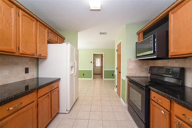 a kitchen with stainless steel appliances granite countertop a refrigerator and a stove top oven
