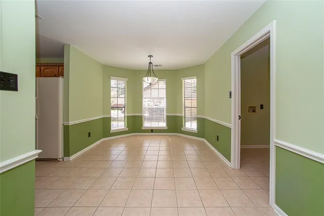 a view of an empty room with window and chandelier