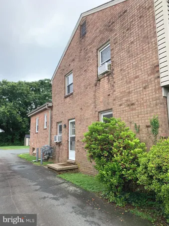 a view of a brick house with a yard and large tree
