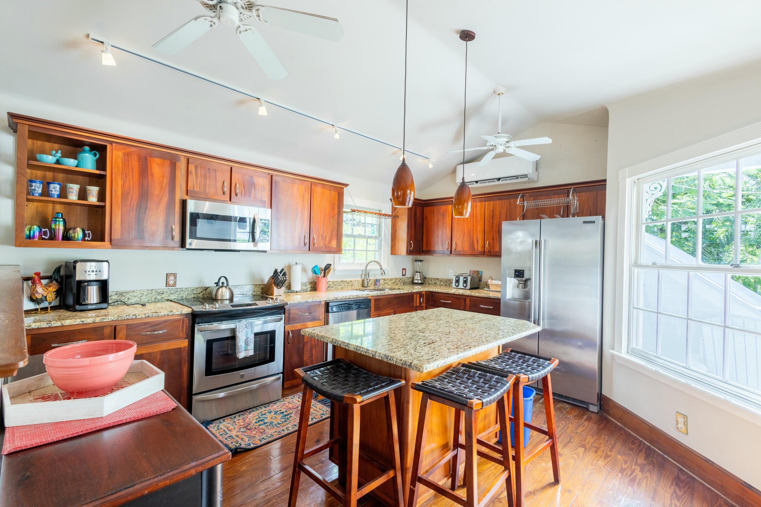 1033 Catherine Street Key West, FL 33040 - Photo 25 of 39 a kitchen with stainless steel appliances granite countertop a stove top oven a refrigerator a sink dishwasher a dining table and chairs with wooden floor