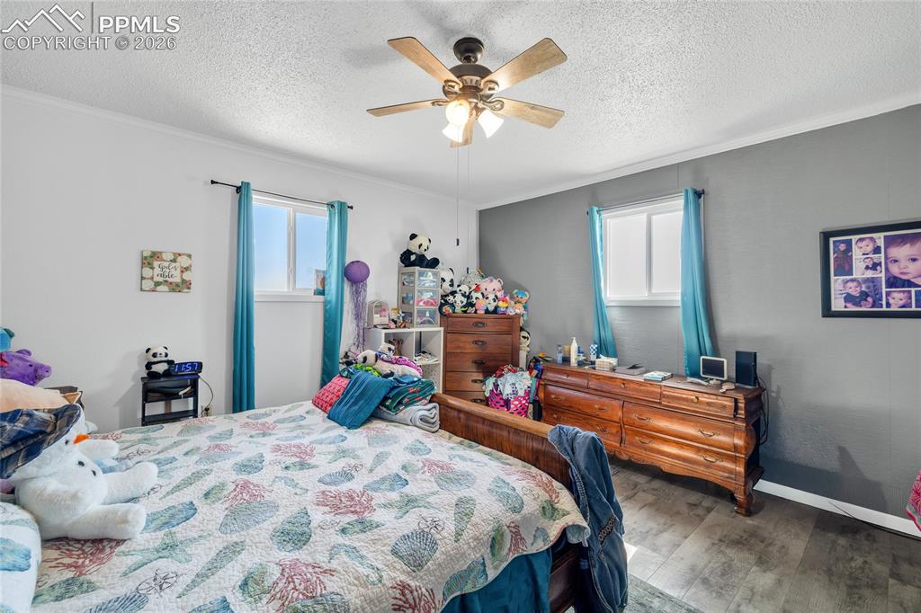 68300 Highway 50 Fowler, CO 81039 - Photo 20 of 49 Bedroom featuring dark wood-style floors, ceiling fan, a textured ceiling, and ornamental molding