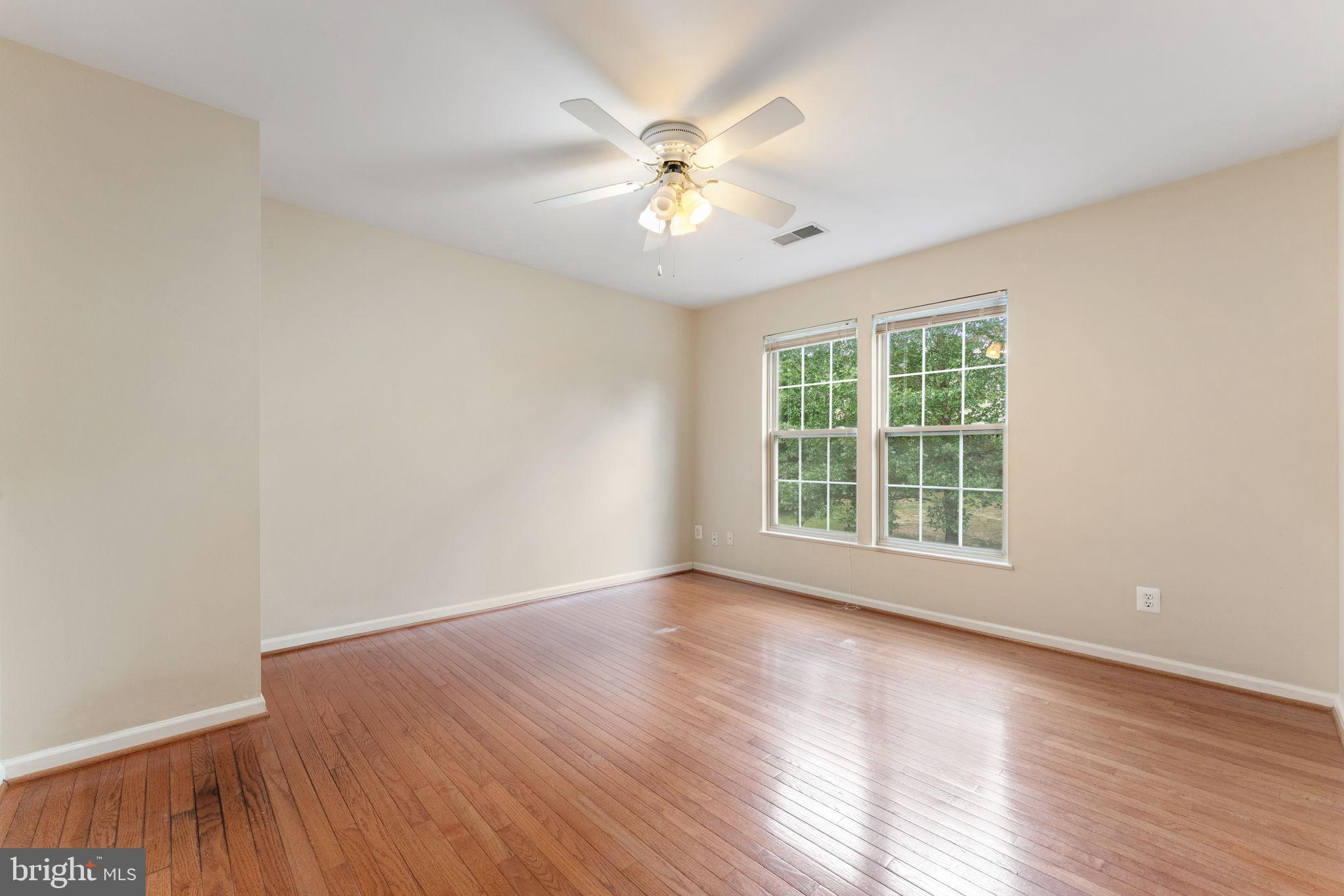 12734 Silvia Loop Woodbridge, VA 22192 - Photo 10 of 22 an empty room with wooden floor chandelier fan and windows