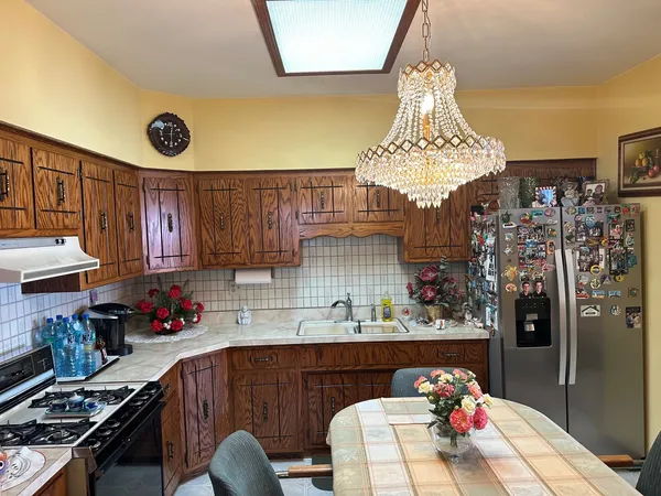 a kitchen with granite countertop a refrigerator dining table and chairs