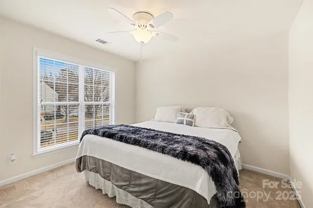 a bedroom with a bed next to a window with a chandelier
