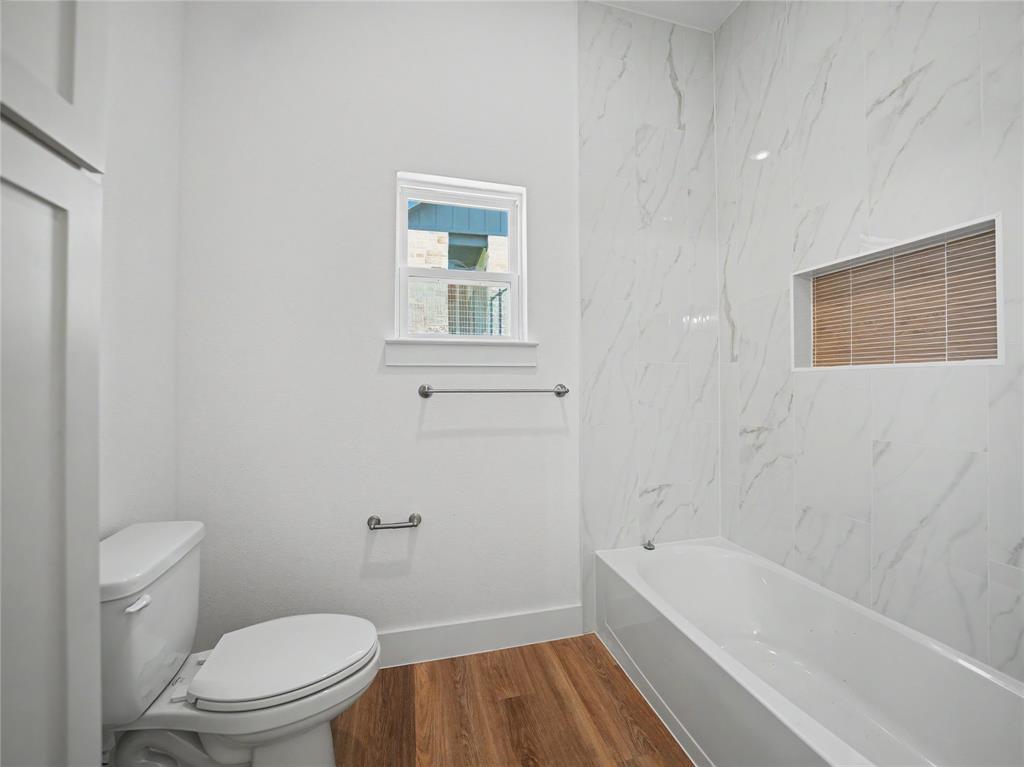 328 Slimp Bluff Azle, TX 76020 - Photo 26 of 30 Bathroom featuring a built-in tub, white subway tile surround with a recessed niche, wood-finish flooring, and a window