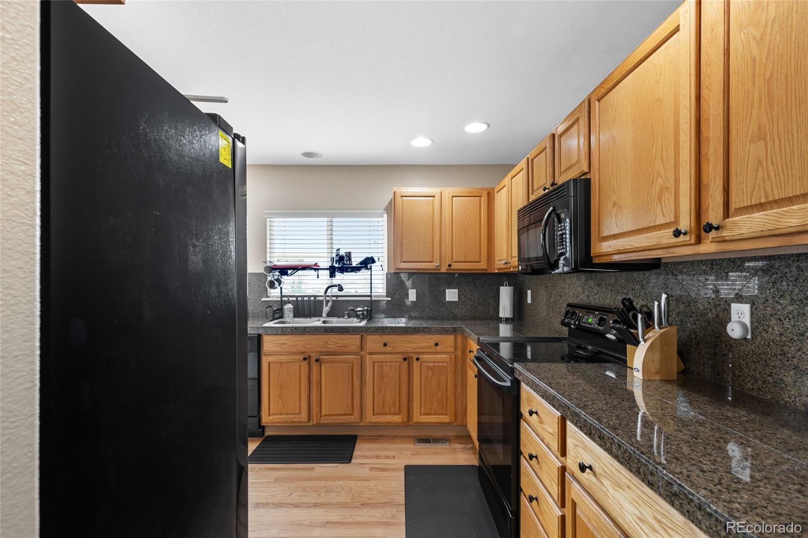 10245 Dusk Street Firestone, CO 80504 - Photo 6 of 24 a kitchen with granite countertop a sink a stove cabinets and a wooden floor