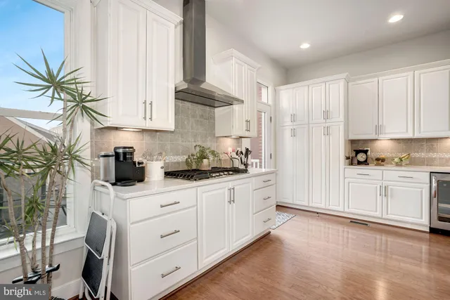 a kitchen with white cabinets and window