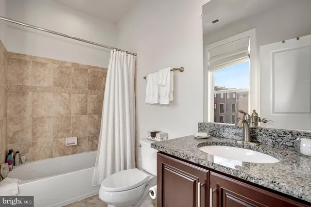 a bathroom with a granite countertop sink a toilet a mirror and shower