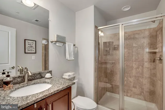 a bathroom with a granite countertop sink toilet a mirror and shower