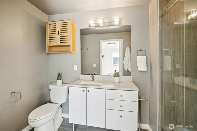 a bathroom with a toilet a sink a mirror a shower a vanity and window