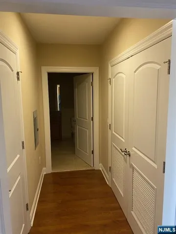 a view of a hallway with wooden floor and a bathroom