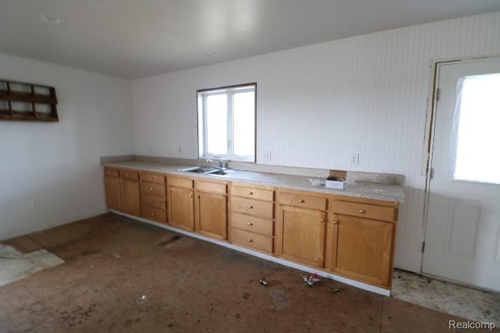 6577 East Deckerville Road Deford, MI 48729 - Photo 7 of 16 Extensive lower cabinetry with wood-finish doors and drawers, a countertop with an integrated sink, and a window above the sink
