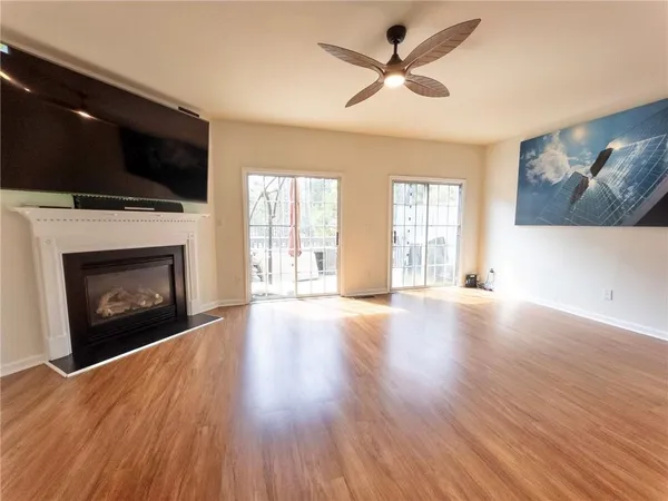 a view of an empty room with wooden floor fireplace and a window