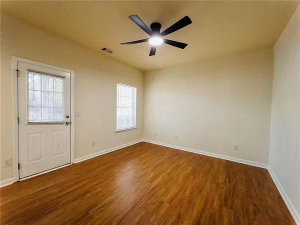 an empty room with wooden floor and windows