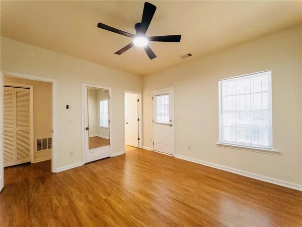 a view of an empty room with wooden floor and a window