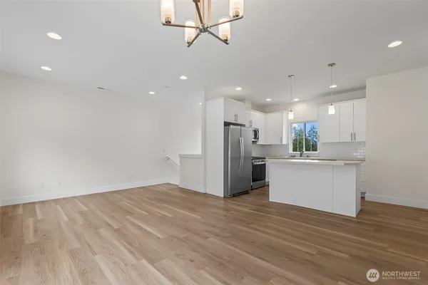 a view of kitchen with kitchen island wooden floor center island and stainless steel appliances