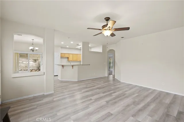 a view of an empty room and window with a kitchen