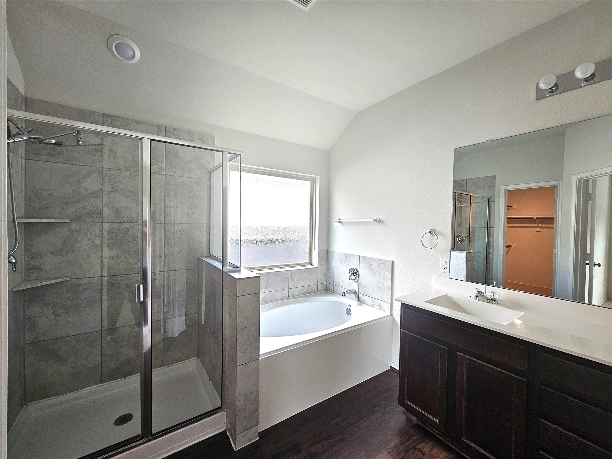 17439 Chester Valley Trail Hockley, TX 77447 - Photo 11 of 22 This modern bathroom features a glass-enclosed shower, a separate soaking tub, and a dual-sink vanity with dark wood cabinetry. It has a bright, airy feel with a window for natural light.
