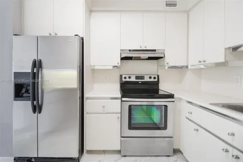 a kitchen with stainless steel appliances white cabinets and a refrigerator