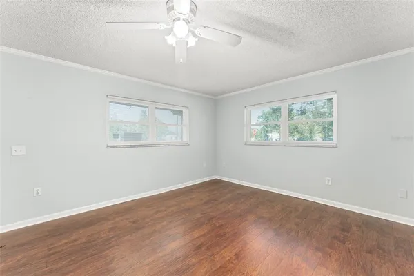 a view of empty room with wooden floor and fan