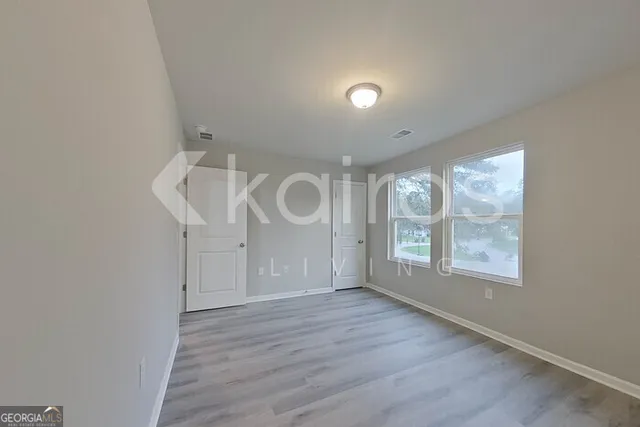 an empty room with wooden floor and windows