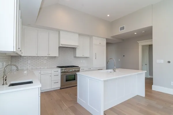 a kitchen with a sink a stove a refrigerator and white cabinets