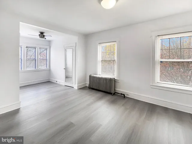 a view of an empty room with a window and wooden floor