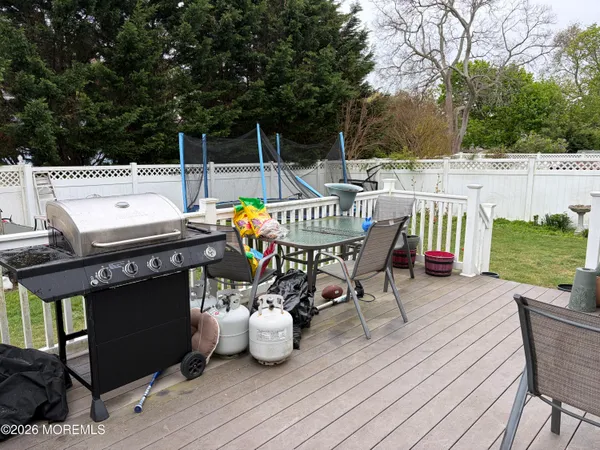 a roof deck with table and chairs a barbeque with wooden floor and fence