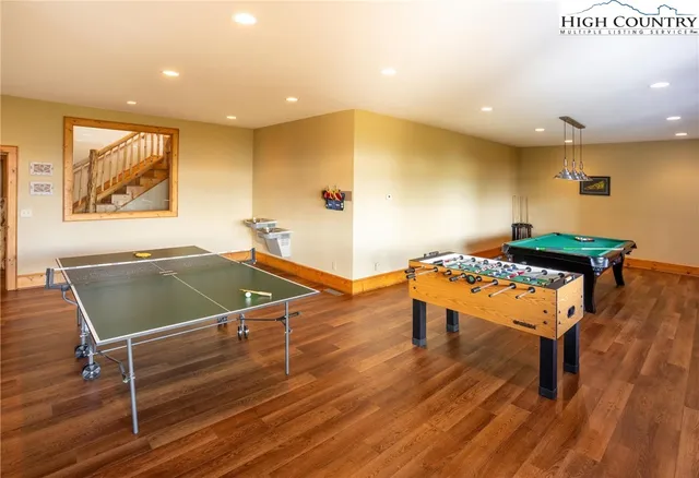 a room with wooden floor pool table and a table