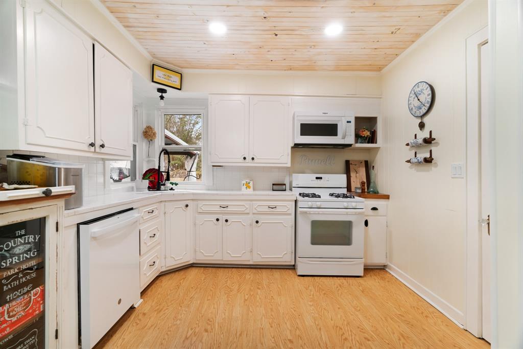 2257 Cleveland Street Paris, TX 75460 - Photo 10 of 39 Kitchen with white appliances, light countertops, wood ceiling, white cabinetry, and light wood-style flooring