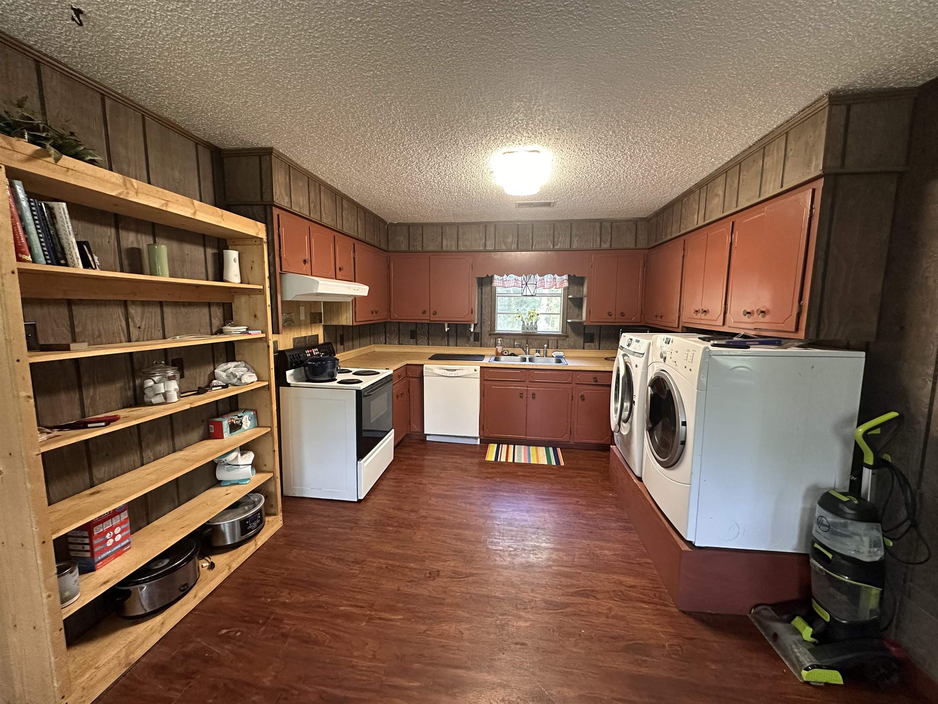 481 Chisholm Lake Camp Road Ripley, TN 38063 - Photo 9 of 12 Kitchen and utility area featuring wood-finish flooring, wood paneling, and an exposed shelving unit