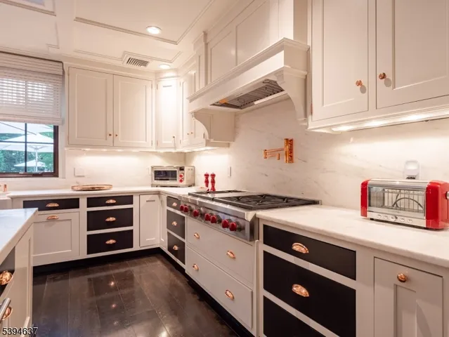a kitchen with stainless steel appliances granite countertop a stove and white cabinets