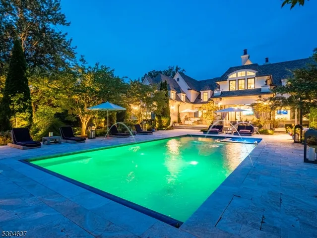 a view of a swimming pool with lawn chairs under an umbrella