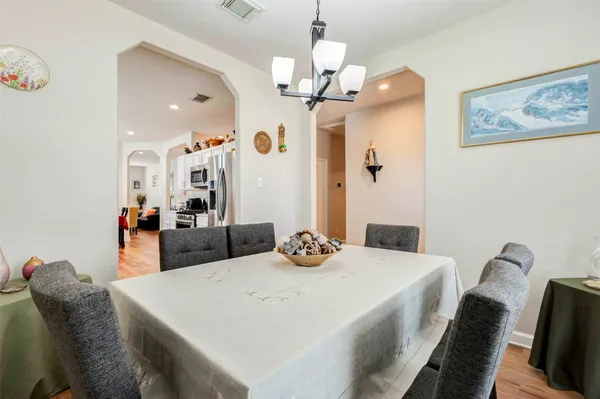 a dining room with wooden floor a chandelier a wooden table and chairs