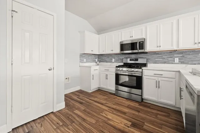 a kitchen with stainless steel appliances white cabinets and a stove top oven