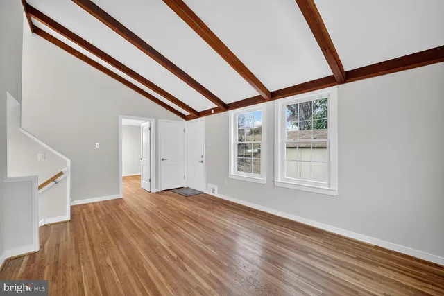 a view of an empty room with wooden floor and windows