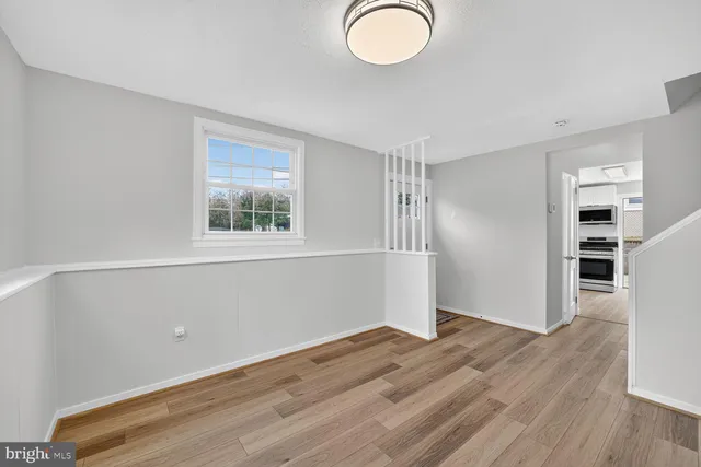 an empty room with wooden floor closet and windows